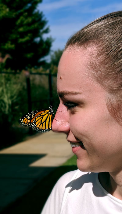 woman with a Monarch Butterly landed on her nose